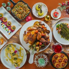 A magnificent Christmas feast captured from above, featuring a whole roasted chicken, ratatouille, pasta, and festive desserts. This flatlay showcases the abundance and variety of a holiday spread.