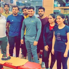 The whole group posing for a picture with the birthday cake. These moments build the strong bonds that make our gym a special place.