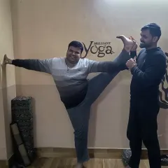Every body is different, and we celebrate each student's unique journey. Here, a student makes great progress in the standing split with wall support and instructor assistance.