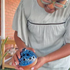 A student admiring her unique, hand-built creation after it has been glaze-fired. The blue and black glaze created a beautiful, speckled effect.