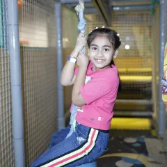 A smiling girl enjoys the ride on our ball swing, a fun feature within our multi-level play structure.