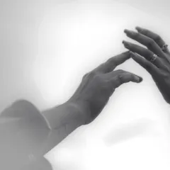 A moody black and white photo of two hands about to touch, symbolizing connection and anticipation. This artistic shot, with its soft focus, creates a sense of intimacy and tenderness.