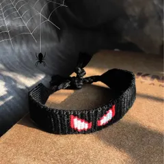A moody shot of the finished black Spider-Man bracelet. The red and white eyes pop against the dark background.