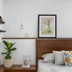 This bedroom detail shows the custom floating nightstand and wooden headboard, with delicate pendant lights adding a touch of elegance.
