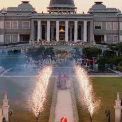 The groom awaits his bride, framed by the palace architecture and a pathway lit by cold pyros. I design every entry to be a cinematic moment, building anticipation for the union to come.