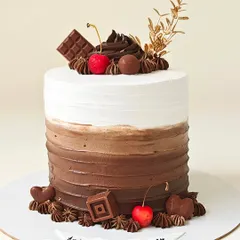 A chocolate lover's dream, this tall cake features a chocolate-to-white ombre effect. It's generously topped with chocolate swirls, cherries, and chocolate hearts.