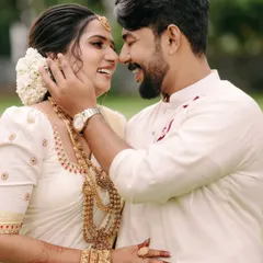 The beautiful smiles of a newly married couple, captured in a close-up that highlights the bride's traditional Kerala jewelry and the groom's loving touch.