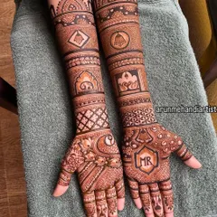 A personalized bridal design featuring the initials "MR" on the palm. The design also includes traditional symbols like a bell and an elephant, blending personal touches with classic motifs.