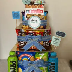 The ultimate Rakhi gift for a foodie sibling. This three-tiered tower is loaded with chips, chocolates, Nutella, and Prime drinks, ensuring there's something for every craving.
