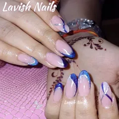 These almond-shaped nails feature a modern French manicure with a vibrant blue glitter tip and a silver accent line, designed to stand out alongside detailed henna.