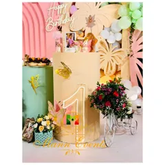 A detail shot from a first birthday party, showing a neon '1' sign, a miniature floral tricycle, and other carefully placed props that add charm and personality.