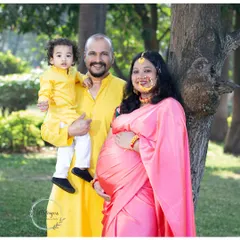 A beautiful family portrait celebrating their heritage. The mom's pink saree and the father and son's matching yellow kurtas create a vibrant and coordinated look for this traditional maternity shoot.