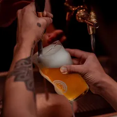 I believe the best moments start with a great pour. Here, you see the craft in action, a stream of golden liquid filling the glass with promise. With 15 beers on tap, each sip has a story, and every pour is a moment waiting to happen.