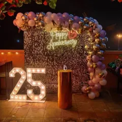 This rooftop anniversary setup combines a silver shimmer wall with a purple and silver balloon arch. The '25' marquee numbers and 'Happy Anniversary' neon sign make it a glamorous and modern way to celebrate a silver jubilee.