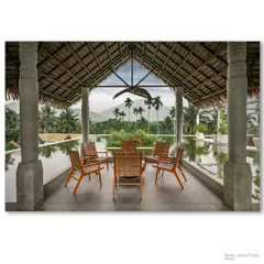 Looking out from a tranquil seating area at Maayaa Resorts in Anaikatti, this photograph frames the majestic mountains through stone pillars. The thatched roof and serene infinity pool create a seamless connection between the architecture and the breathtaking natural landscape, promising a peaceful escape.