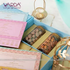 A lovely pastel blue gift box containing two large jars of premium almonds. This hamper is paired with a set of matching invitation cards in shades of pink, blue, and orange, creating a soft and elegant aesthetic.