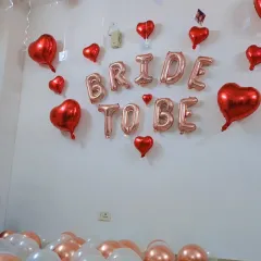 A close-up of the 'BRIDE TO BE' foil balloon banner, surrounded by red heart-shaped balloons for a romantic and celebratory feel.
