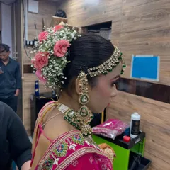 An intricate bridal bun adorned with fresh pink roses and baby's breath. This is a classic and romantic choice for a wedding day hairstyle.