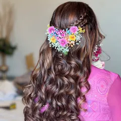 A creative and romantic hairstyle for a Mehendi ceremony. This half-up style features a heart shape made from colorful fresh flowers and baby's breath.