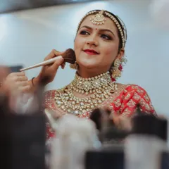 A behind the scenes moment, adding the final touches to this royal bridal makeup. You can see the smooth, airbrushed finish of the base and the carefully applied lipstick that completes her look.