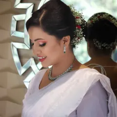 A side profile of this soft and dreamy look. The elegant hair updo, adorned with fresh baby's breath and roses, perfectly complemented her simple white saree.