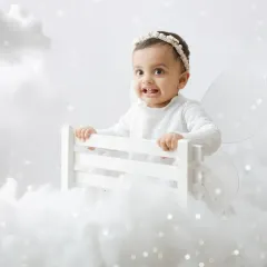 A little fairy in the clouds. This dreamy, all-white setup with soft clouds and sparkling lights creates a magical, heavenly portrait.