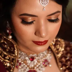 A close-up of a classic combination: bold golden glitter on the lids paired with a rich, glossy red lip. This look is the epitome of confidence and timeless bridal glamour.