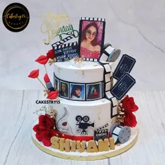 A dazzling two-tier Retro Bollywood theme cake for a wife's birthday. This 3kg chocolate cake is decorated with a film reel, movie clapper, and edible photos for a cinematic tribute.