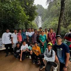 A group of students at a beautiful waterfall, combining learning with fun and adventure. I ensure a balanced itinerary for all my school trips.