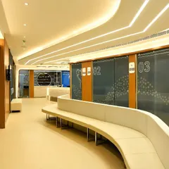 The waiting corridor in the eye hospital features a long, curved bench and clearly numbered consultation rooms. This spatial design facilitates easy patient flow and enhances comfort during their visit.