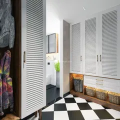 The walk-in closet and vanity area of the Svamitva Terravana project, with louvered white wardrobe doors and a striking black-and-white checkerboard floor.