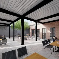 This view from under the covered patio shows the relationship between the indoor and outdoor spaces. The use of exposed brick walls and large window frames helps connect the different areas of the cafe seamlessly.