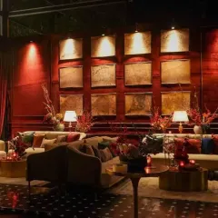 We designed multiple lounge areas to encourage conversation. This setup features plush sofas, a dramatic art wall lit from above, and deep red velvet curtains, creating a cozy and sophisticated corner within the larger event space.