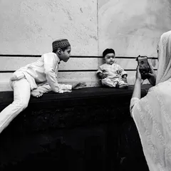 A candid black and white moment in Jama Masjid, where a mother takes a photo of her two young sons. It's a universal story of family and memory set within a historic location.