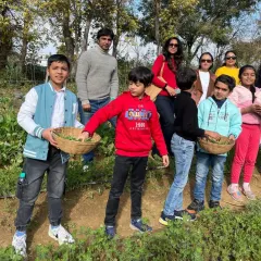A lovely family group pauses for a photo during their weekend outing. With baskets full of freshly picked greens, they are all smiles after a fun day of harvesting on the farm.
