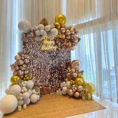 A full view of the rose gold and white birthday setup. The combination of the shimmering wall, the warm glow of the neon sign, and the soft texture of the balloons creates a look of pure elegance.