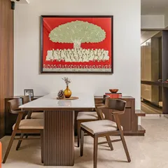 The dining area is centered around a beautiful wooden table and sleek chairs. The space is elevated by a custom-made 'Tree of Life' art piece from Rajasthan, adding cultural elegance and symbolism.