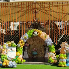 Combining traditional elements with a fun theme. For this outdoor Mundan ceremony entrance, I created a balloon arch with jungle animals and paired it with beautiful hanging garlands of marigold flowers for a festive, welcoming touch.