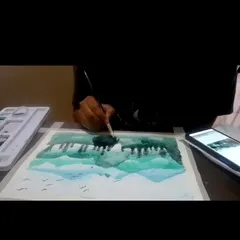 A student participating in one of our online watercolor classes, learning to paint a forest and lake scene from home.