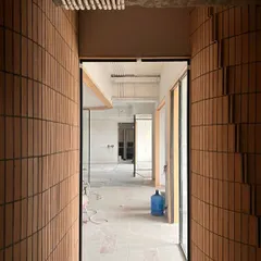 A corridor lined with vertically laid bricks, creating a unique textured effect. This view from a work-in-progress site shows how we use common materials in unconventional ways.