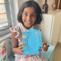 A happy girl holds up the pirate-themed photo frame she created using decoupage techniques. A fun way to frame your favorite memories.