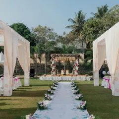 A beautiful outdoor wedding aisle, featuring a custom-printed runner with a delicate leaf pattern. The aisle leads to a floral mandap, all set up on a lush green lawn for a fresh and modern ceremony.