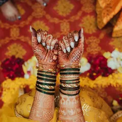 A detailed shot of the bride's hands, showcasing the intricate mehendi design and traditional green bangles.