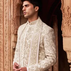 A closer look at the craftsmanship. The delicate, hand embroidered floral patterns on this ivory sherwani showcase a commitment to artisanal finesse and understated detail.