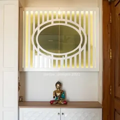 A simple entrance foyer is reimagined into a serene and welcoming space. The 'before' was a plain wall, and the 'after' features a custom shoe cabinet with textured doors and a beautiful backlit decorative panel, creating a peaceful first impression.