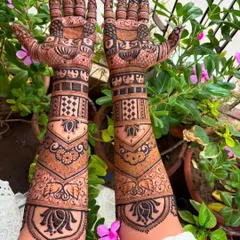 This design combines geometric jaali patterns with soft lotus and elephant motifs. The V-shape on the forearm creates a modern and elegant silhouette.