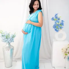 Simplicity and serenity. Dressed in a flowing sky-blue gown, the mother-to-be cradles her bump in our minimalist white studio setup. This clean, bright style creates a feeling of peace and pure anticipation.