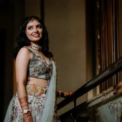 A full-length portrait of the bride in her floral lehenga, posing elegantly on a staircase.