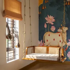 In the living room of our Banashankari residence, a traditional wooden swing becomes a playful centerpiece. This space embodies my approach of integrating nostalgic elements into a modern, light-filled home, using Jaisalmer stone flooring and a wood-and-cane false ceiling to create an earthy, grounded feel.