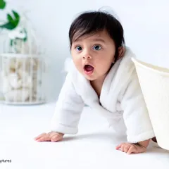 A curious peek from behind the tub. The clean, all-white set with minimal props keeps the focus on your baby's expressions during the bath session.
